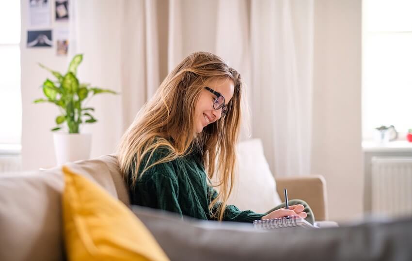 smiling woman writing in a gratitude journal