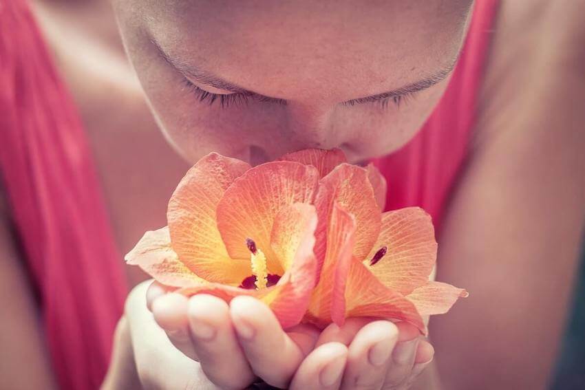 woman smelling the flowers she's holding in her hands