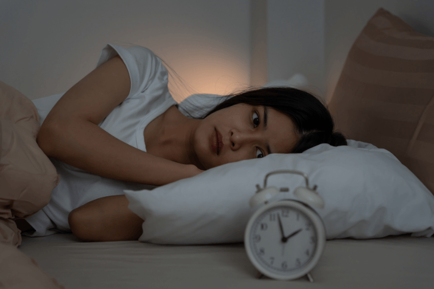 woman laying awake in bed, ruminating