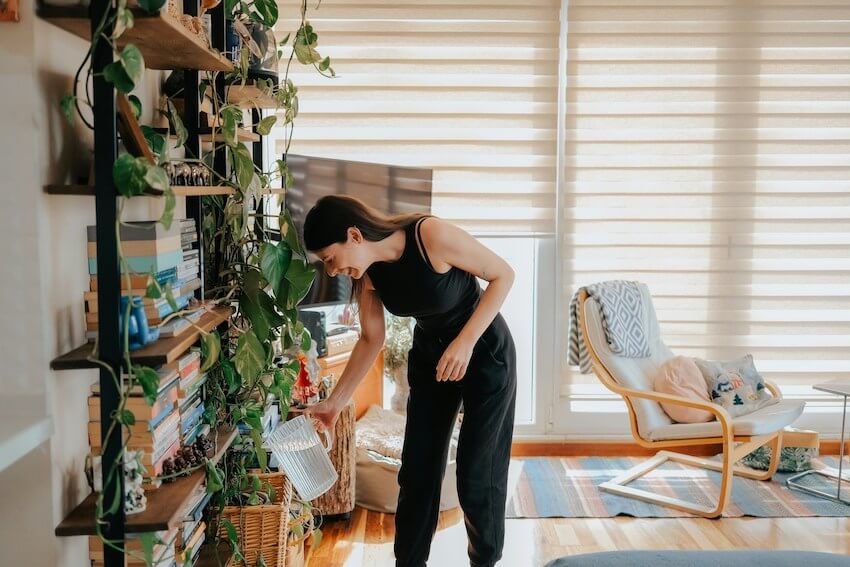smiling woman watering her indoor plants