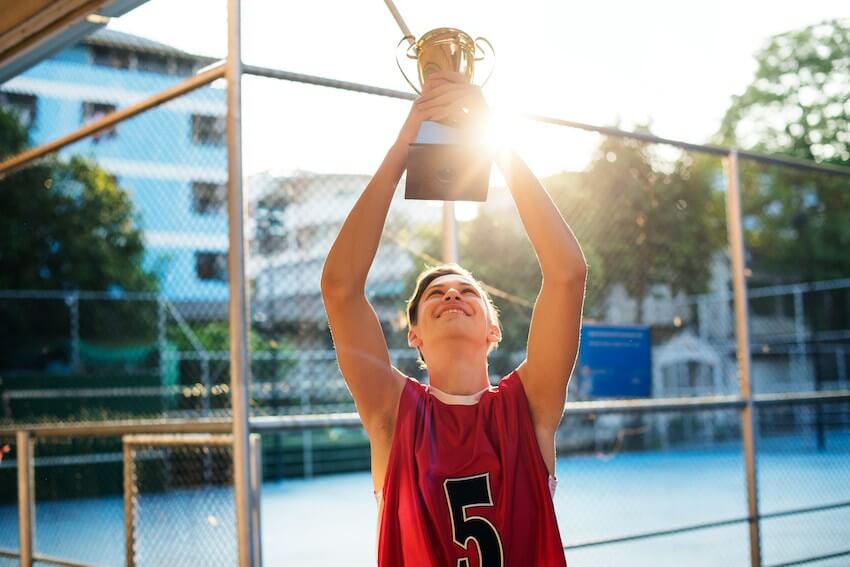 smiling man holding a trophy over his head