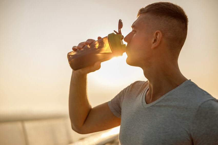 man drinking from a water bottle at sunset