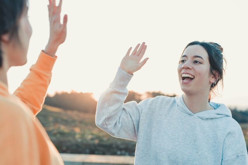 two smiling women high-fiving each other