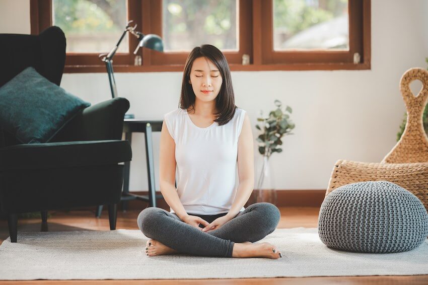 woman sitting on the ground in a meditative pose with her eyes closed