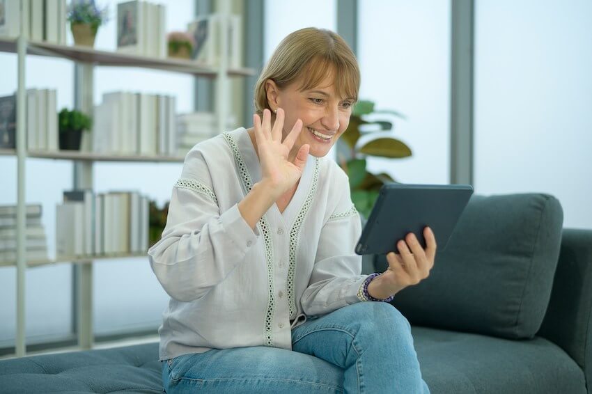 smiling woman waving to family on video chat