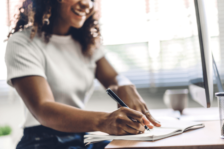 smiling woman writing down a name on paper