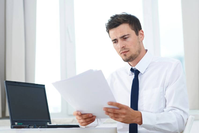 A businessman reading documents at his desk with a worried expression, the moment before you realize contracts alone cannot show you how to build trust in a relationship.