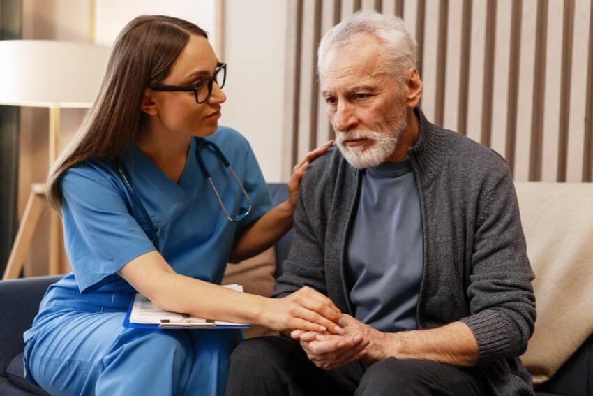 A female doctor holding an elderly patient's hand and speaking to him gently, one of the most powerful empathy examples in everyday medical care.