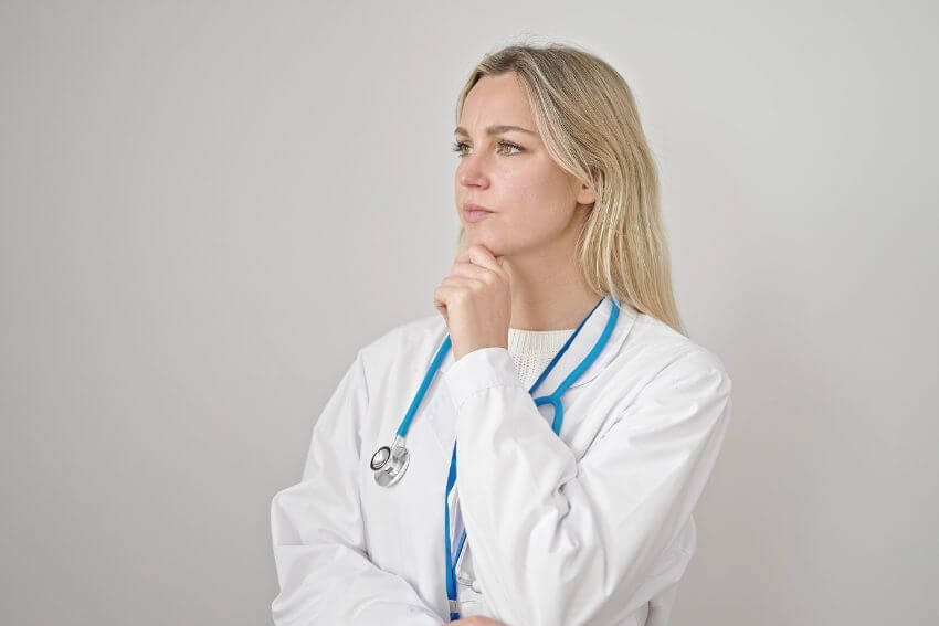 A female doctor pausing in quiet thought, the kind of reflective presence that empathy examples in medicine are really made of.