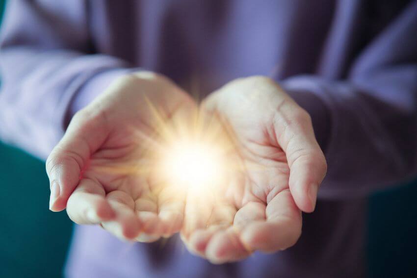 Two open hands holding a warm light, a simple visual of the abundance mindset that says there is always enough to give.